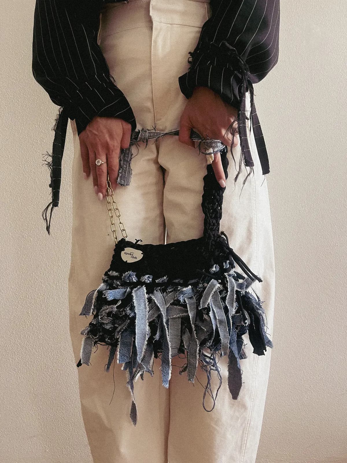 Černá háčkovaná kabelka Strappyjeans s džínovými třásněmi, detail v rukou